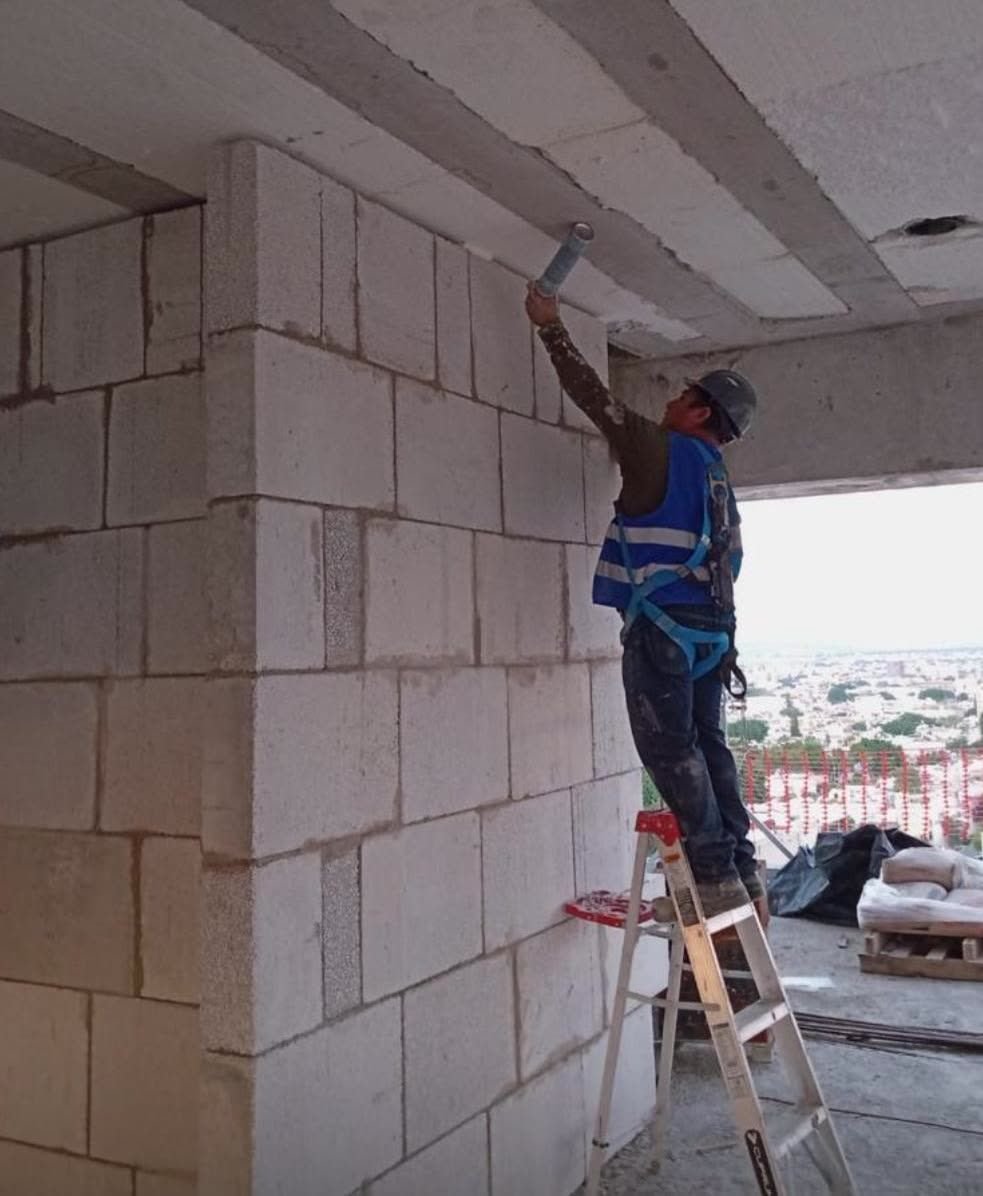 Muro divisorio de bloques de concreto aligerado levantado hasta la losa en un edificio en obra.